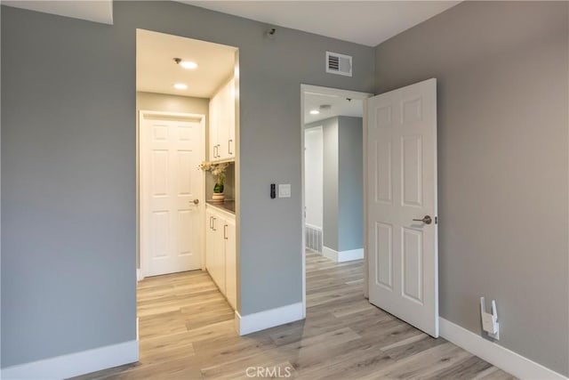 unfurnished bedroom with ensuite bathroom and light wood-type flooring