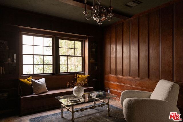 sitting room with wood walls and a notable chandelier