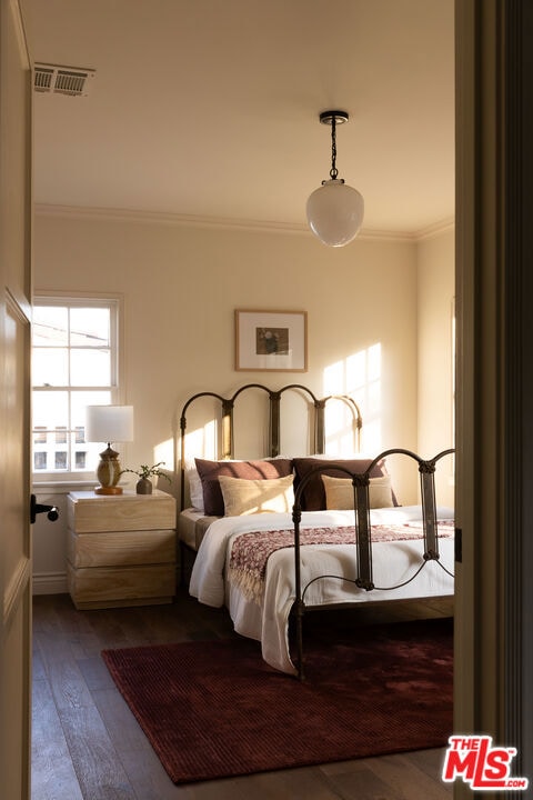 bedroom with ornamental molding and hardwood / wood-style floors