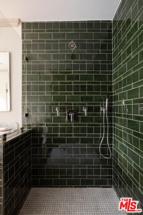 bathroom with a tile shower and ornamental molding