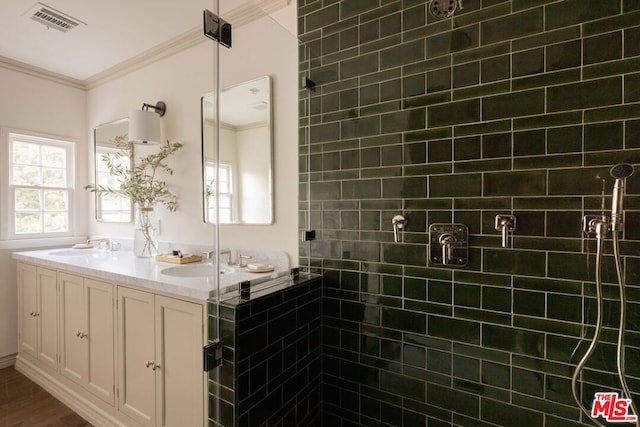 bathroom with a shower with shower door, vanity, and crown molding