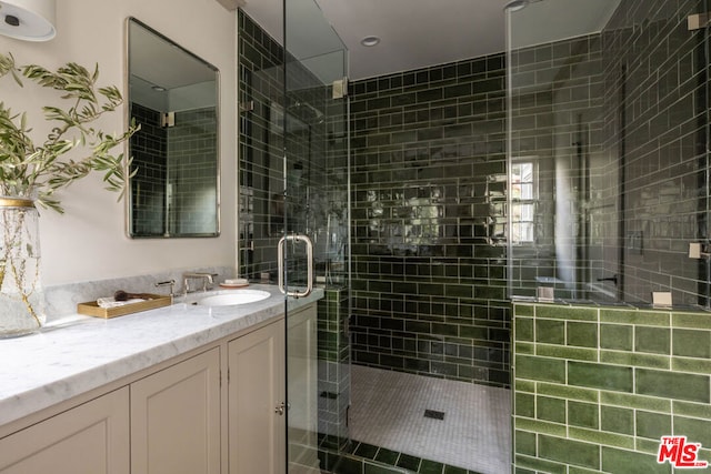 bathroom featuring a shower with shower door and vanity