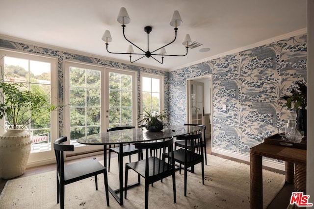 dining room with a notable chandelier, plenty of natural light, ornamental molding, and light hardwood / wood-style floors