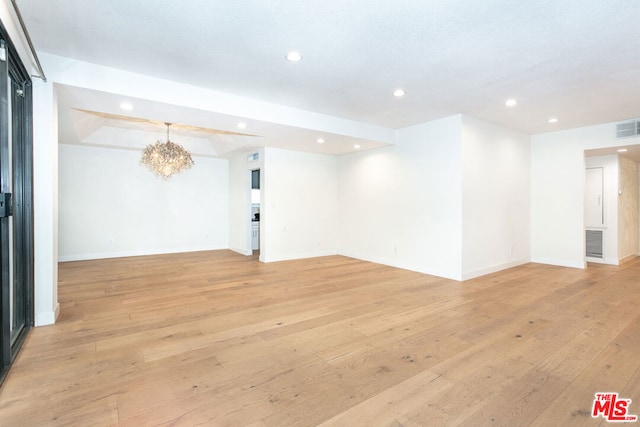 empty room featuring an inviting chandelier and light hardwood / wood-style floors