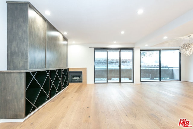 unfurnished room with an inviting chandelier and light hardwood / wood-style flooring