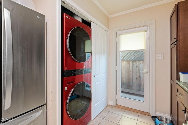 washroom featuring light tile patterned floors, stacked washer / drying machine, and crown molding