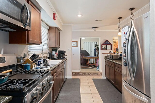 kitchen featuring decorative light fixtures, sink, appliances with stainless steel finishes, ornamental molding, and light tile patterned floors