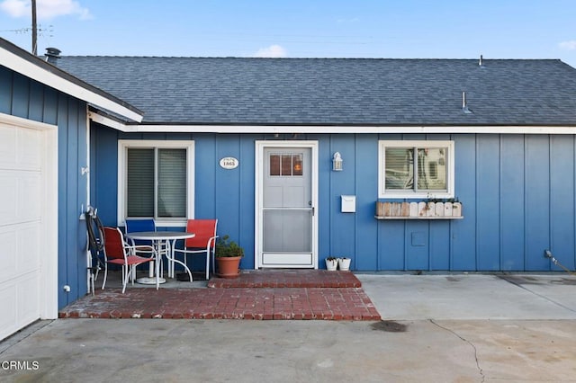 view of exterior entry with a patio area and a garage