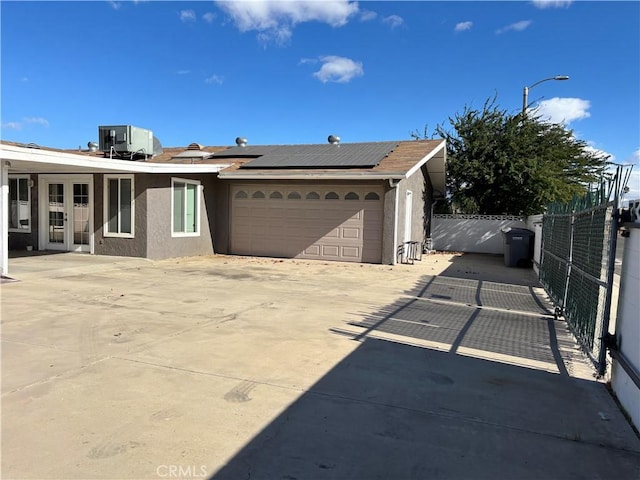 view of front of property featuring a garage, cooling unit, and solar panels