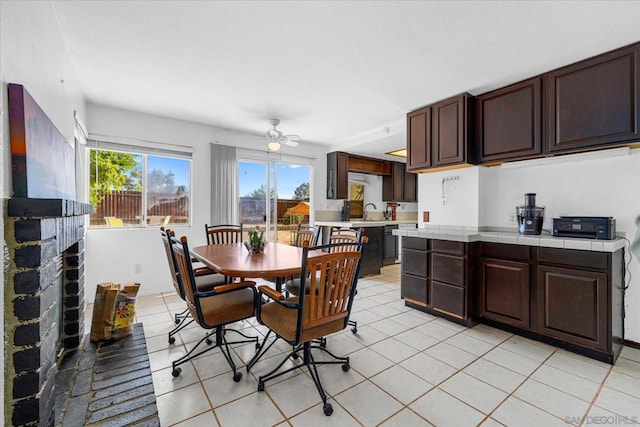 dining space with ceiling fan, light tile patterned floors, and a fireplace