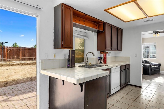 kitchen with ceiling fan, sink, tile countertops, light tile patterned flooring, and white dishwasher