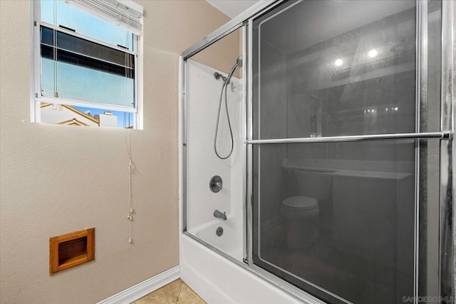 bathroom featuring toilet, combined bath / shower with glass door, and tile patterned floors