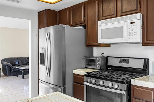 kitchen featuring light tile patterned flooring, stainless steel appliances, and tile counters