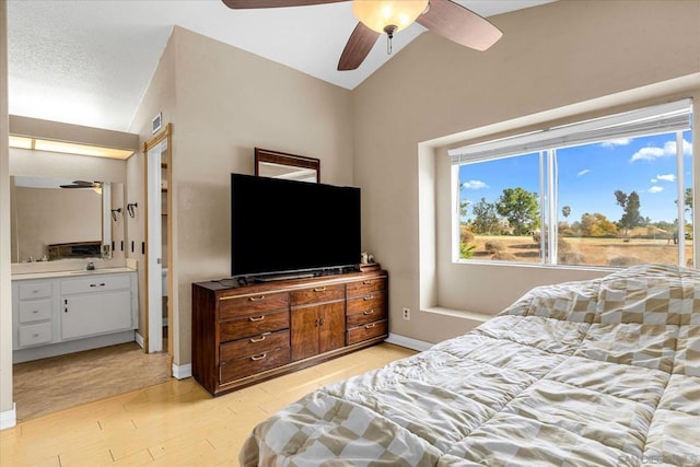 bedroom with ceiling fan, light wood-type flooring, connected bathroom, and lofted ceiling