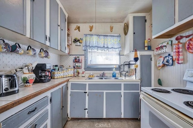 kitchen featuring stove, gray cabinetry, and sink