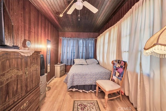 bedroom featuring ceiling fan, light hardwood / wood-style flooring, wooden walls, and wooden ceiling