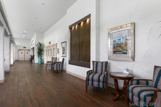 hall featuring dark wood-type flooring and a towering ceiling