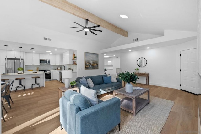 living room with ceiling fan, sink, light hardwood / wood-style floors, and lofted ceiling with beams