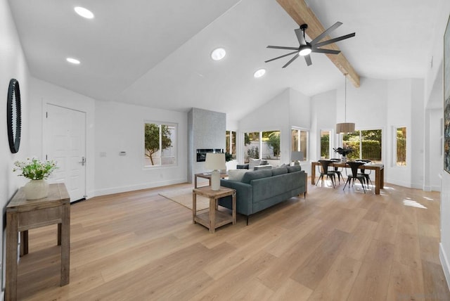 living room featuring light hardwood / wood-style floors, ceiling fan, a wealth of natural light, and beamed ceiling