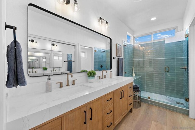 bathroom with a shower with shower door, hardwood / wood-style floors, and vanity