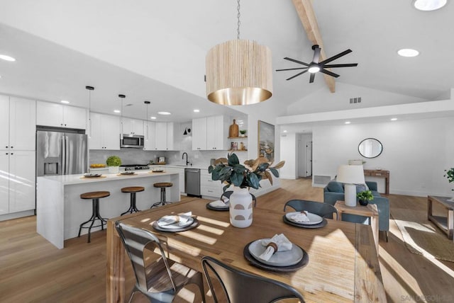 dining room with ceiling fan, light hardwood / wood-style flooring, and beamed ceiling