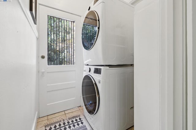 clothes washing area featuring light tile patterned floors and stacked washing maching and dryer