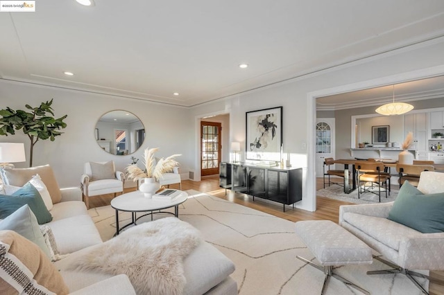 living room with crown molding and light hardwood / wood-style floors