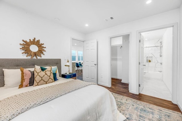 bedroom featuring dark wood-type flooring, a spacious closet, a closet, and ensuite bath