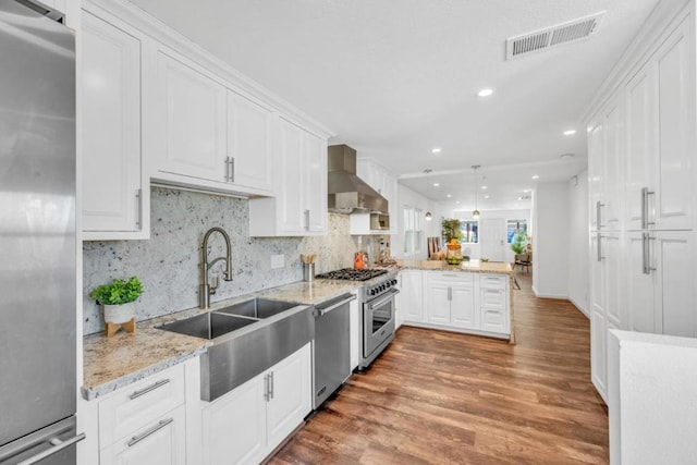 kitchen with sink, white cabinets, wall chimney range hood, and appliances with stainless steel finishes