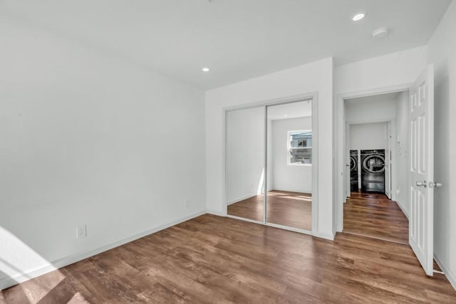 unfurnished bedroom featuring hardwood / wood-style floors, a closet, and washing machine and clothes dryer