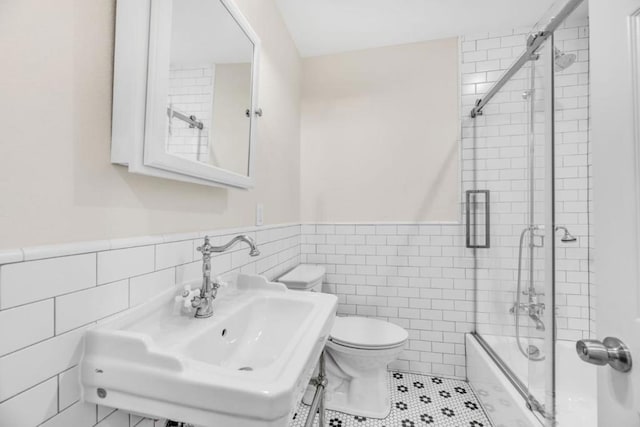 full bathroom with tile patterned flooring, toilet, enclosed tub / shower combo, tile walls, and sink