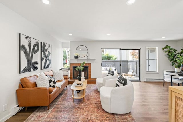 living room featuring a tiled fireplace, a baseboard radiator, and dark hardwood / wood-style floors