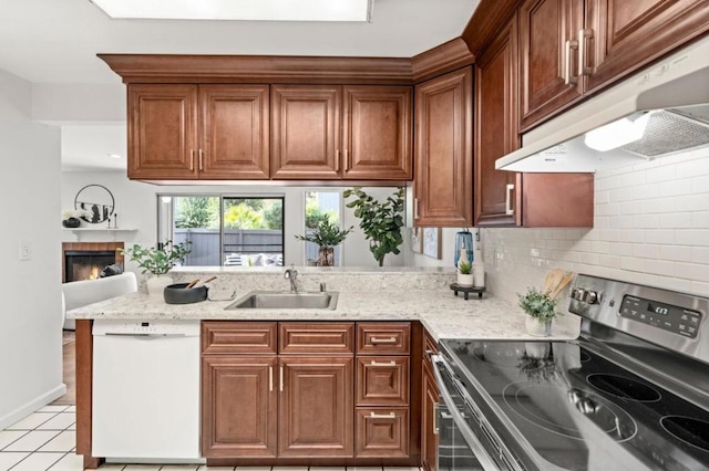 kitchen with sink, electric range, dishwasher, a tile fireplace, and light stone countertops