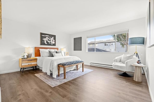 bedroom with baseboard heating and hardwood / wood-style flooring