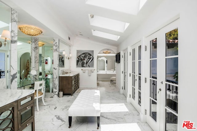 bathroom featuring vaulted ceiling with skylight, french doors, and vanity