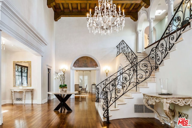 foyer entrance featuring decorative columns, a towering ceiling, beam ceiling, and wood ceiling