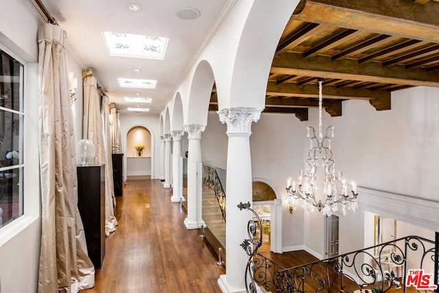 hall featuring dark hardwood / wood-style flooring, a chandelier, ornamental molding, and decorative columns