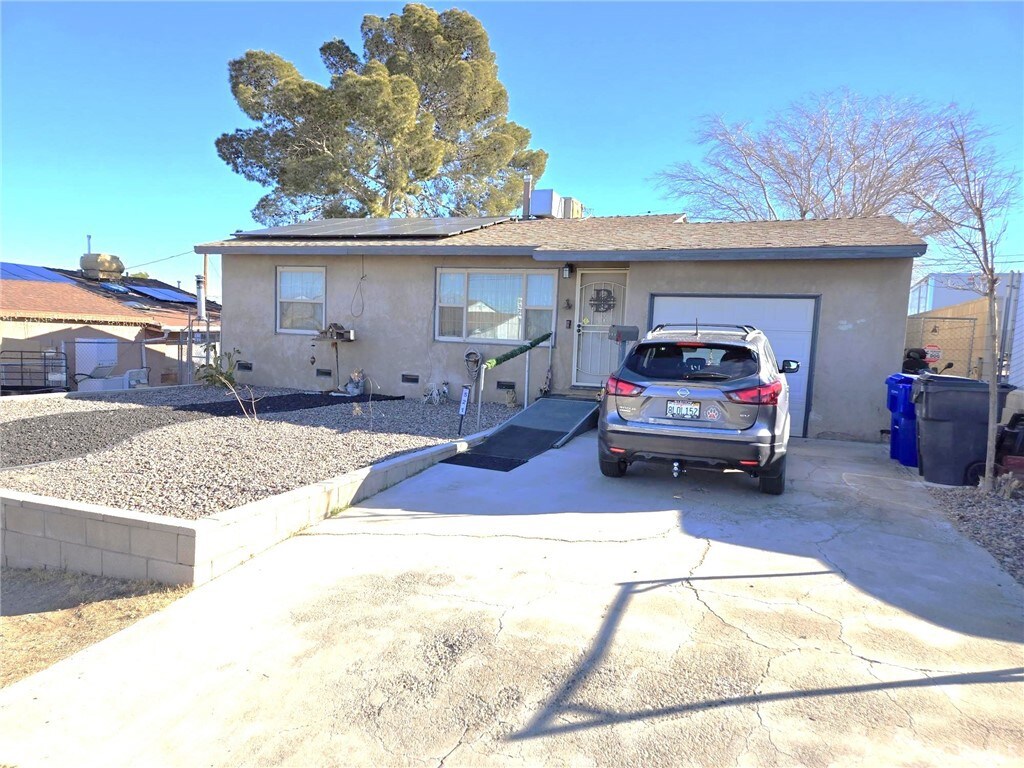 ranch-style home with a garage and solar panels