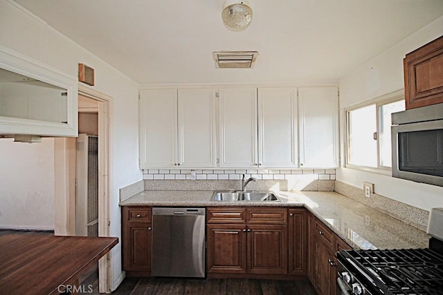 kitchen featuring appliances with stainless steel finishes, light stone countertops, and sink