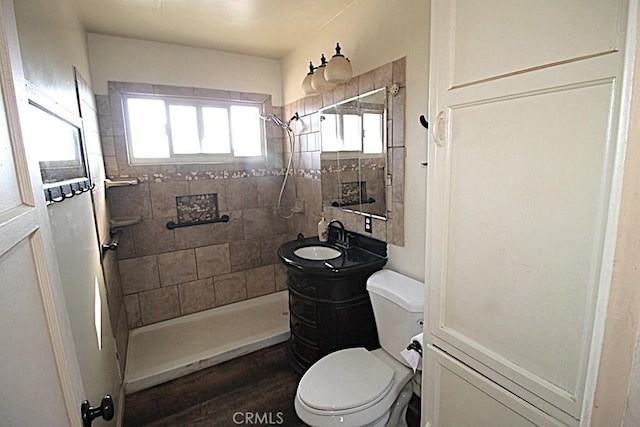 bathroom featuring a tile shower, vanity, and toilet