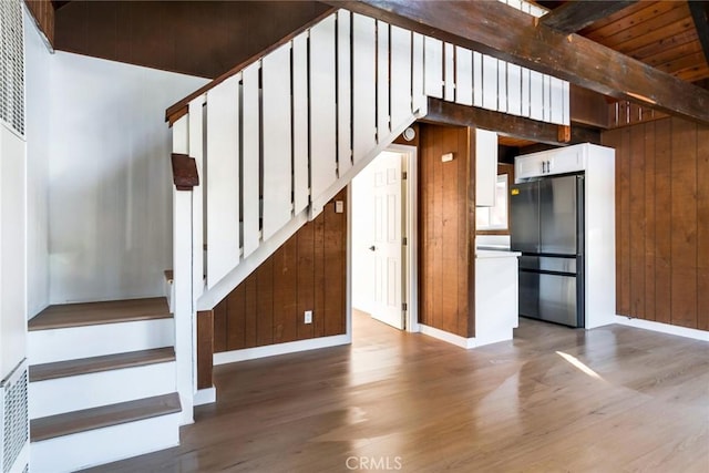 stairs with wooden ceiling, wood-type flooring, wood walls, and beamed ceiling