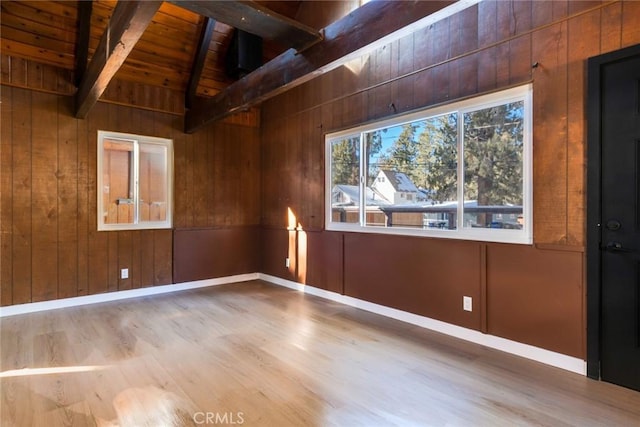 empty room featuring wooden ceiling, hardwood / wood-style floors, lofted ceiling with beams, and wooden walls