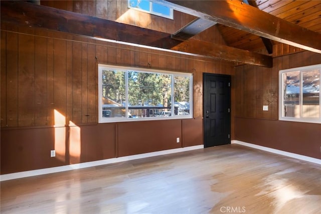 empty room featuring wooden ceiling, wood-type flooring, wood walls, and lofted ceiling with beams