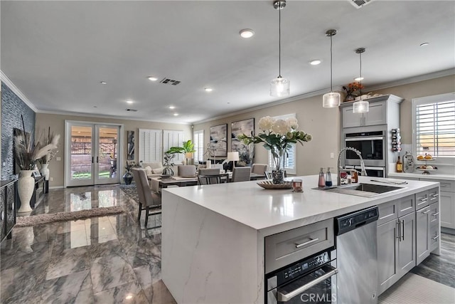 kitchen featuring plenty of natural light, appliances with stainless steel finishes, gray cabinetry, and an island with sink