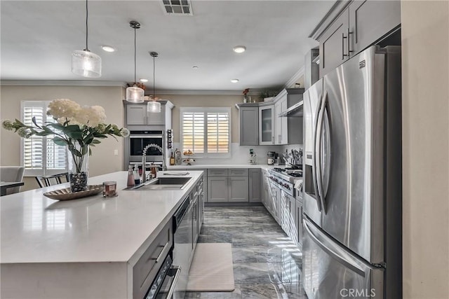 kitchen with sink, appliances with stainless steel finishes, gray cabinetry, and an island with sink