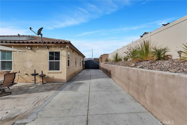 view of property exterior featuring solar panels and a patio