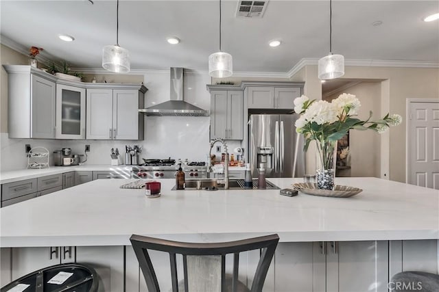 kitchen with decorative light fixtures, wall chimney range hood, and gray cabinets