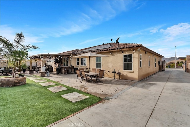 rear view of property with a pergola, a lawn, and a patio