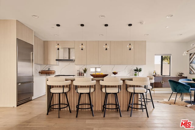 kitchen with built in fridge, pendant lighting, a center island, and light hardwood / wood-style flooring