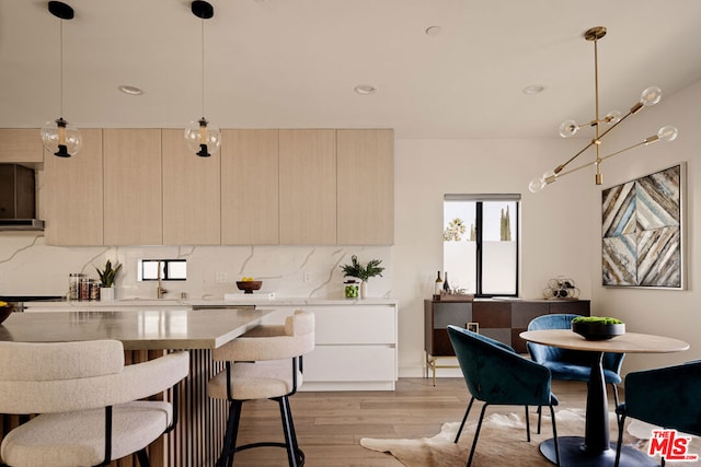 kitchen featuring decorative light fixtures, backsplash, and light hardwood / wood-style floors